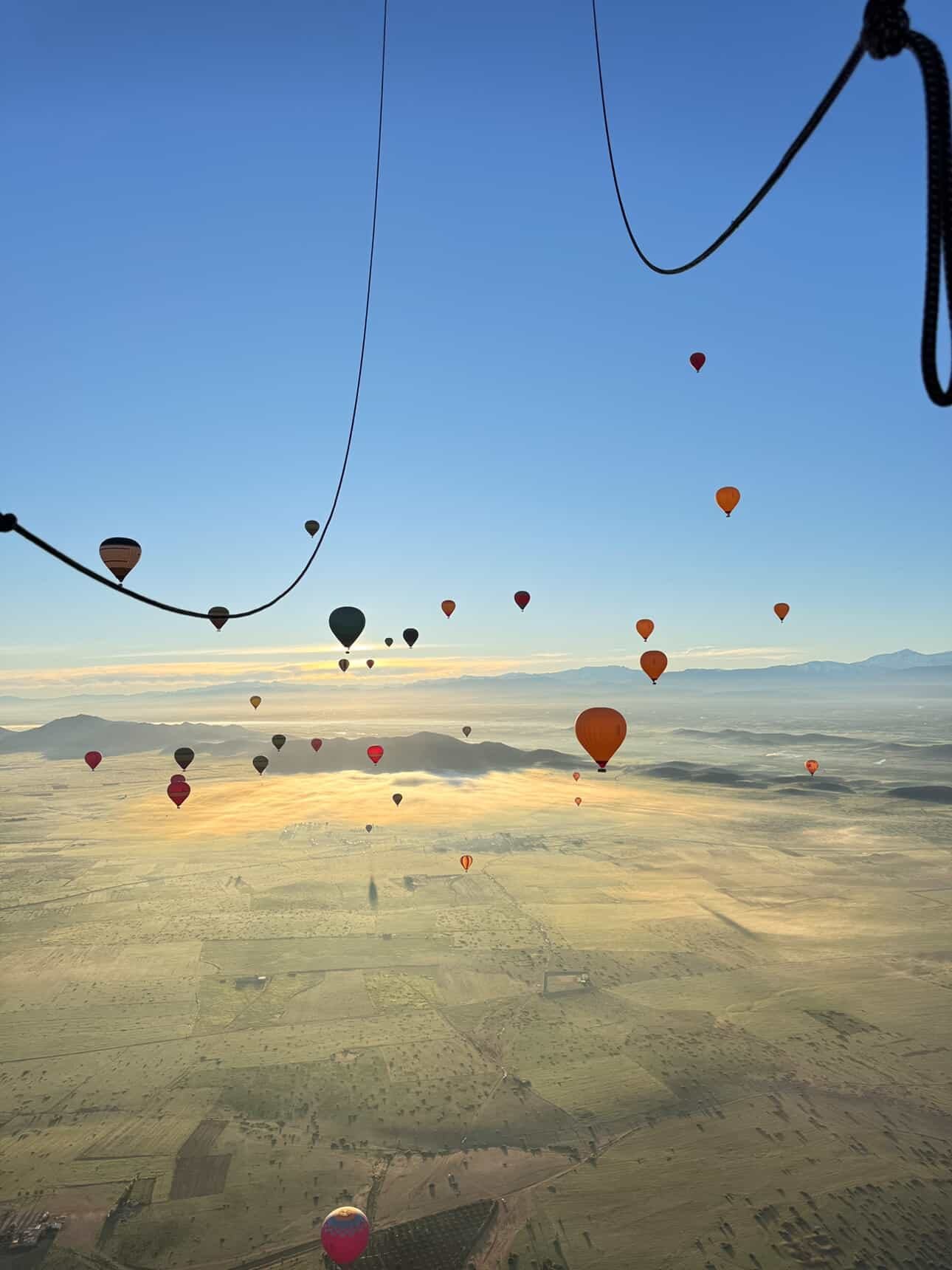 Globos aerostáticos sobre campos con niebla cerca de Marrakech al amanecer, vistos desde una cesta