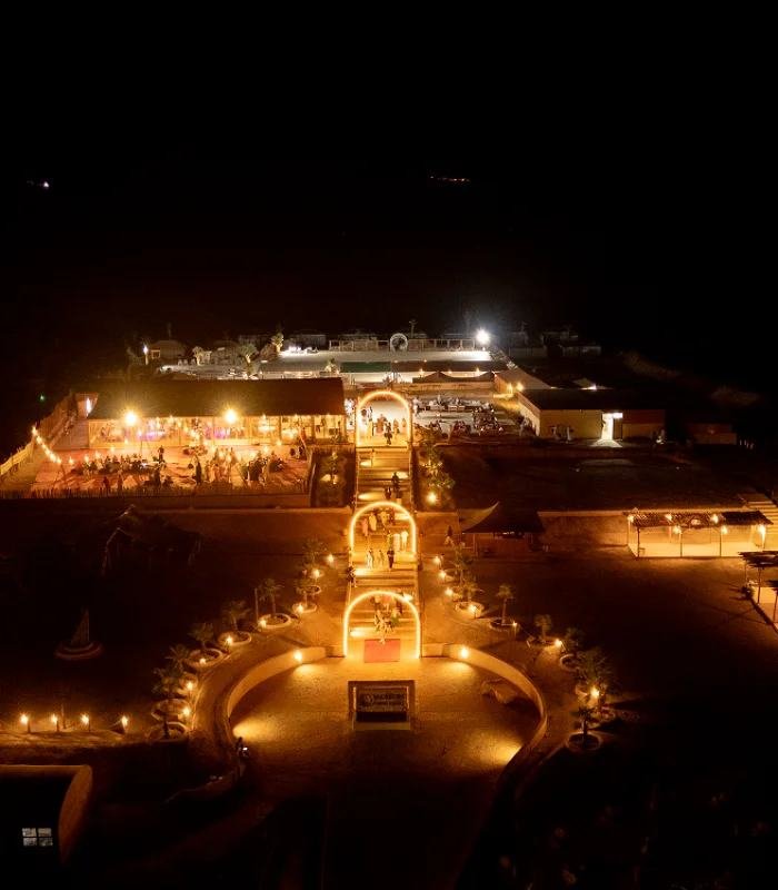 Un campamento de lujo en el desierto iluminado de noche, visto desde arriba