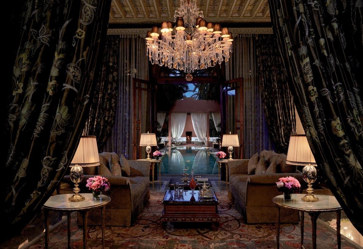 Salón privado con lámpara de araña abierto a una piscina en un riad de lujo de Marrakech